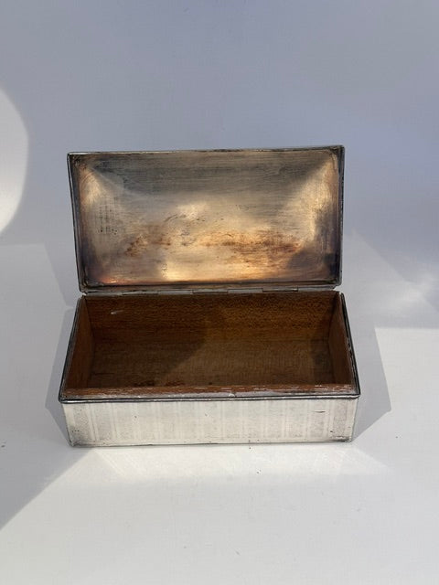Open silver-plate cigarette box showing the hinged lid and wood-lined interior