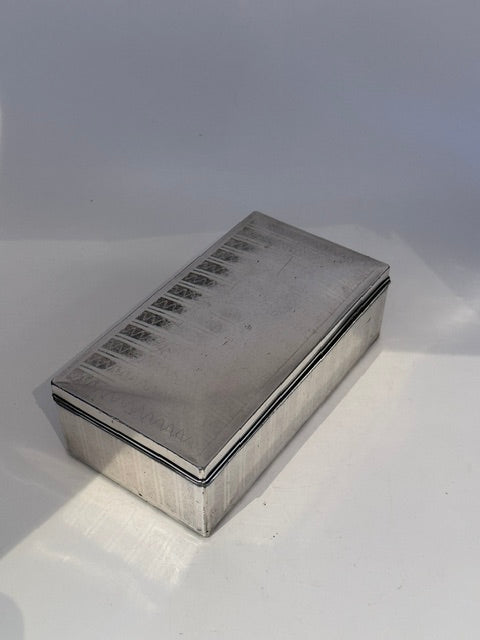 Angled view of the cigarette box showing its engine-turned Deco lid pattern