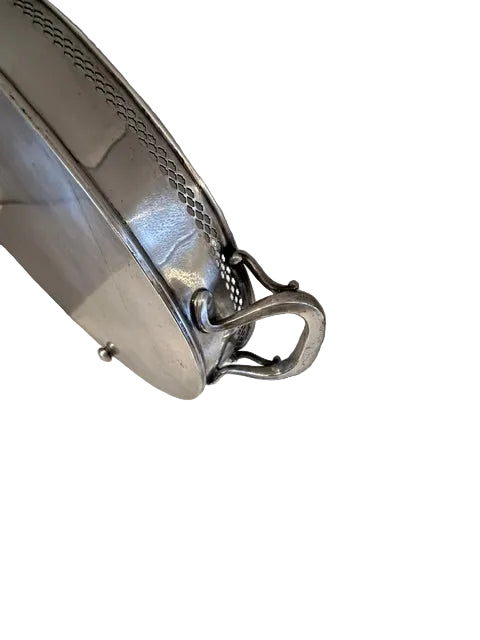 Close-up of the oval tray's pierced rim and ornate loop handle