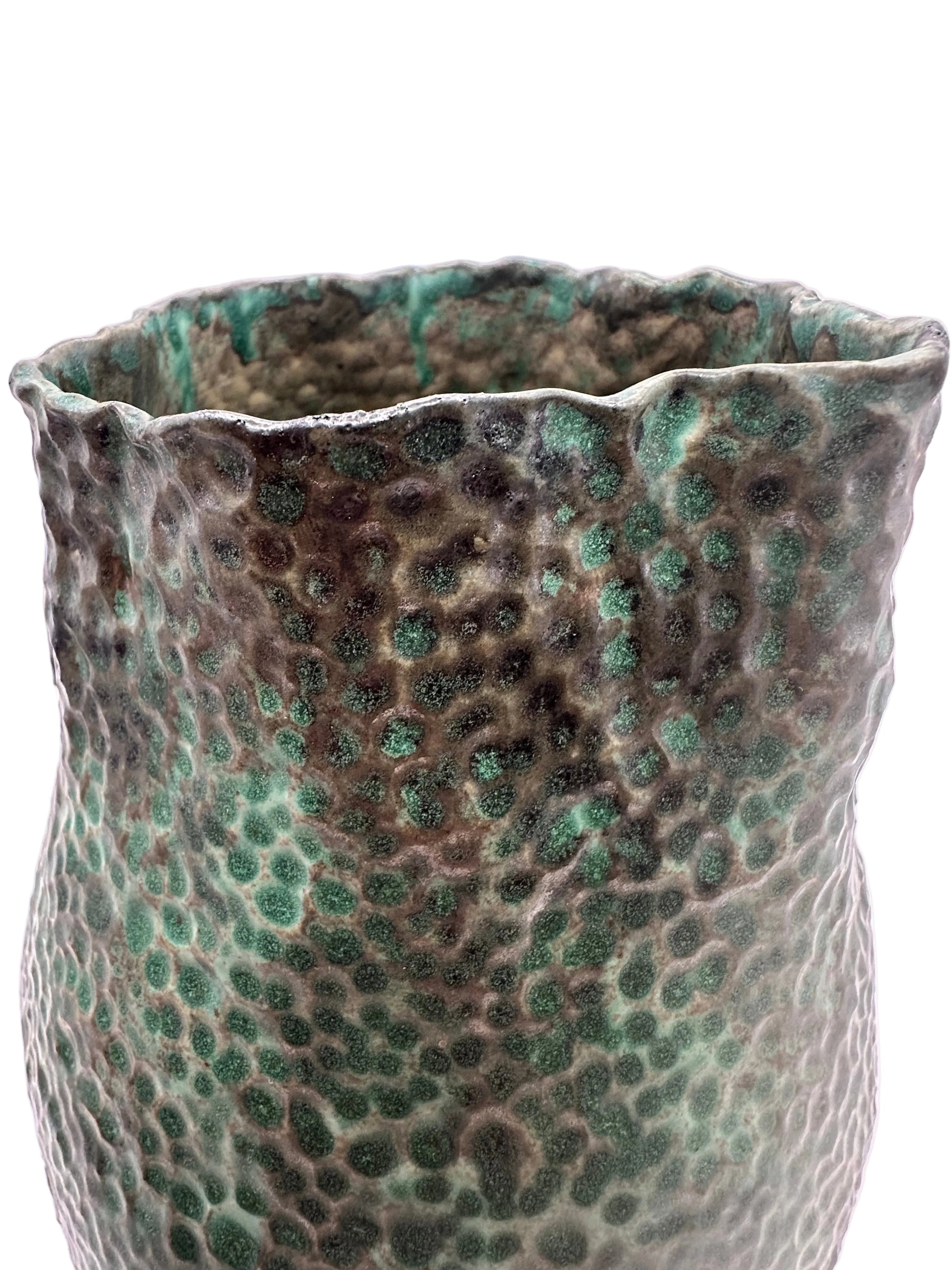 Close-up of the vessel's hammered texture and ruffled rim in green and bronze glaze