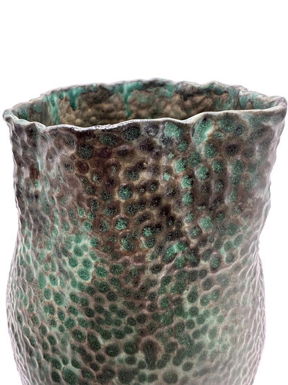 Close-up of the vessel's hammered texture and ruffled rim in green and bronze glaze