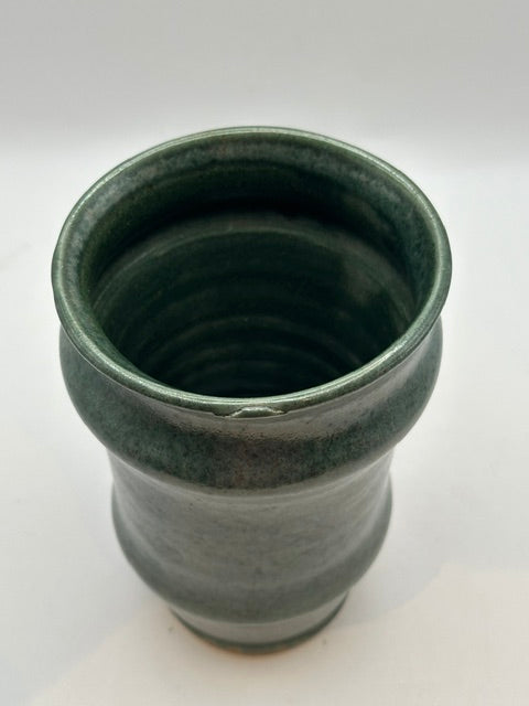 Green satin-glazed stoneware vessel holding white orchids, styled on white background