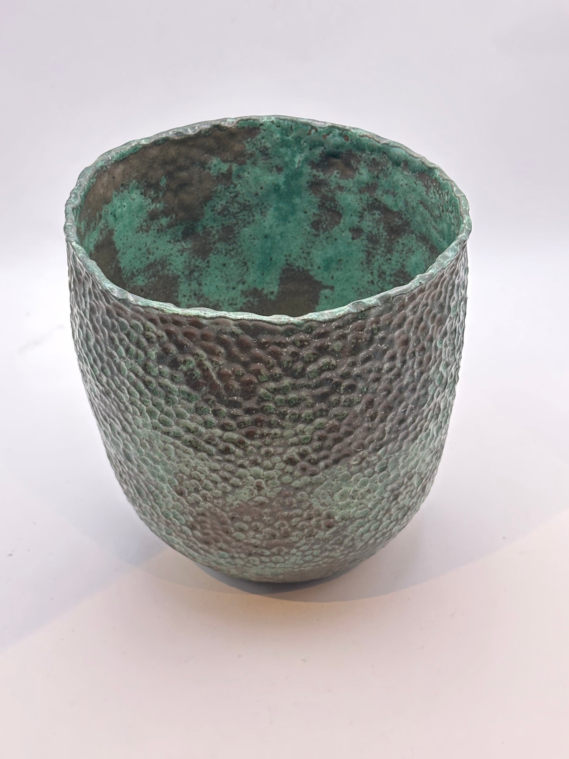 Wide-mouth stoneware vessel from above showing its bright verdigris interior