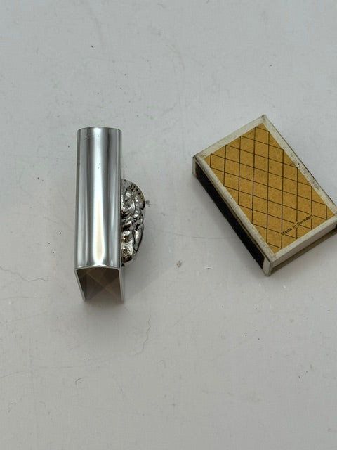 Silver-plate matchbox cover standing upright next to its matchbox, showing open end
