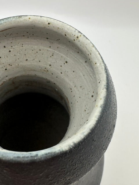 Close-up into black stoneware vase mouth, speckled grey glazed interior.