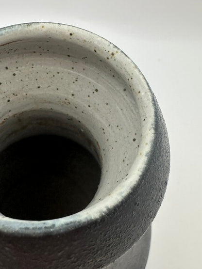Close-up into black stoneware vase mouth, speckled grey glazed interior.
