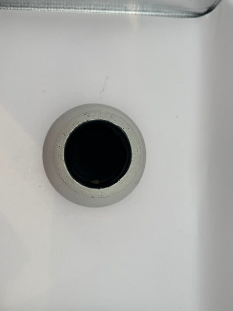 Top-down view into the white stoneware vessel's dark mouth and speckled rim.
