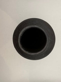 Handmade ceramic vase viewed top-down, dark circular mouth on white surface