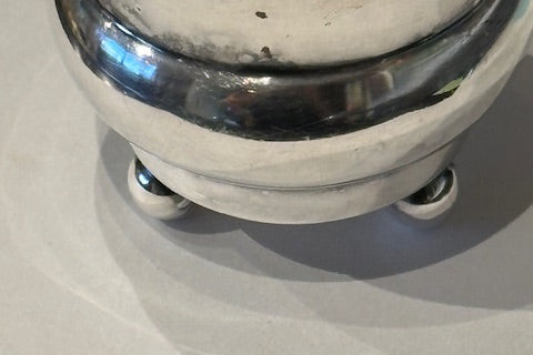 Close-up of toothpick holder's lower body and three small ball feet on grey surface