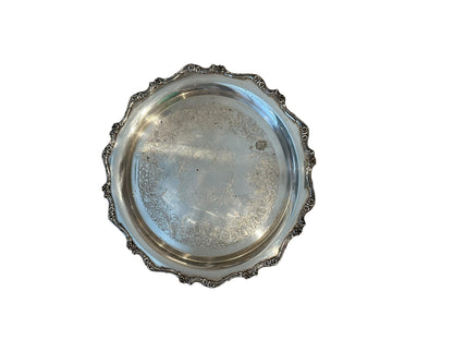 Vintage round silverplate serving tray, scalloped scroll border framing engraved floral center, top view