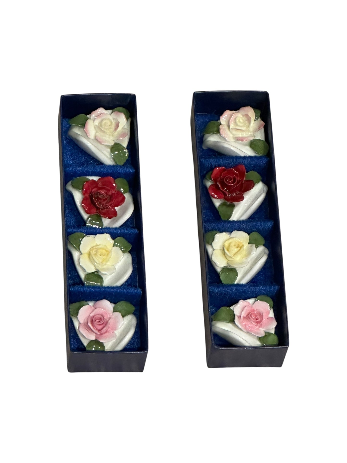 Porcelain rose place card holders arranged in two navy presentation boxes, angled view