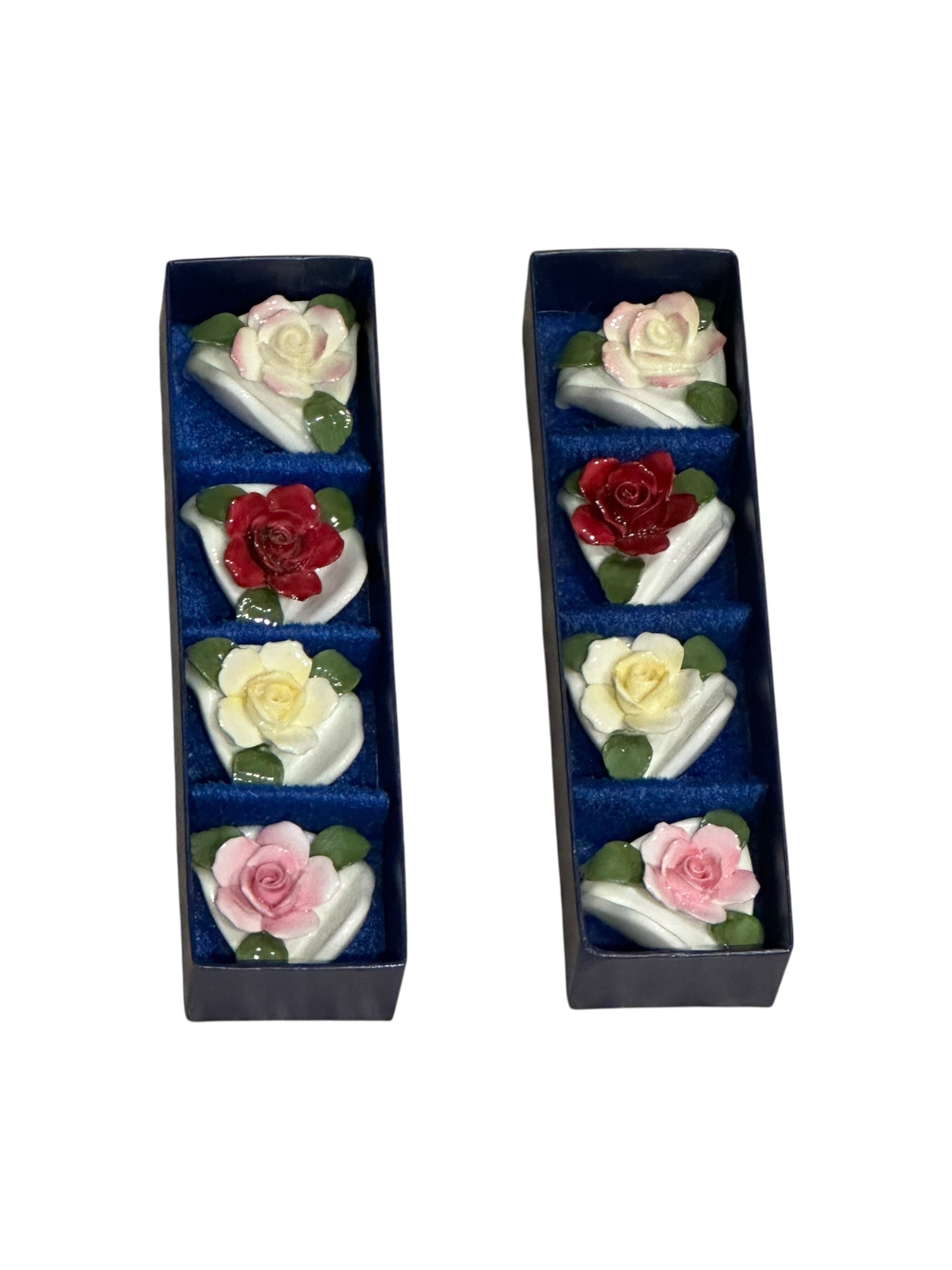 Porcelain rose place card holders arranged in two navy presentation boxes, angled view