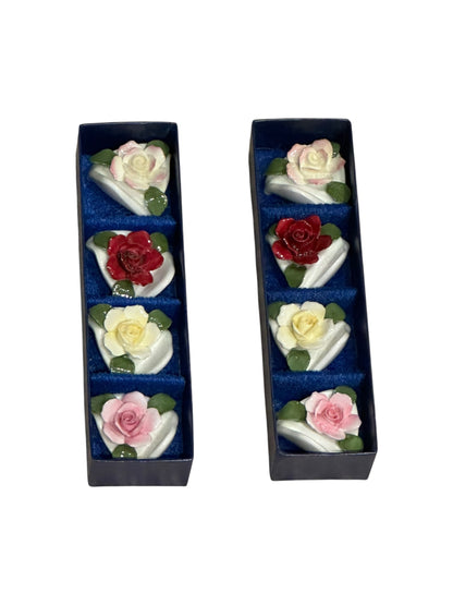 Porcelain rose place card holders arranged in two navy presentation boxes, angled view
