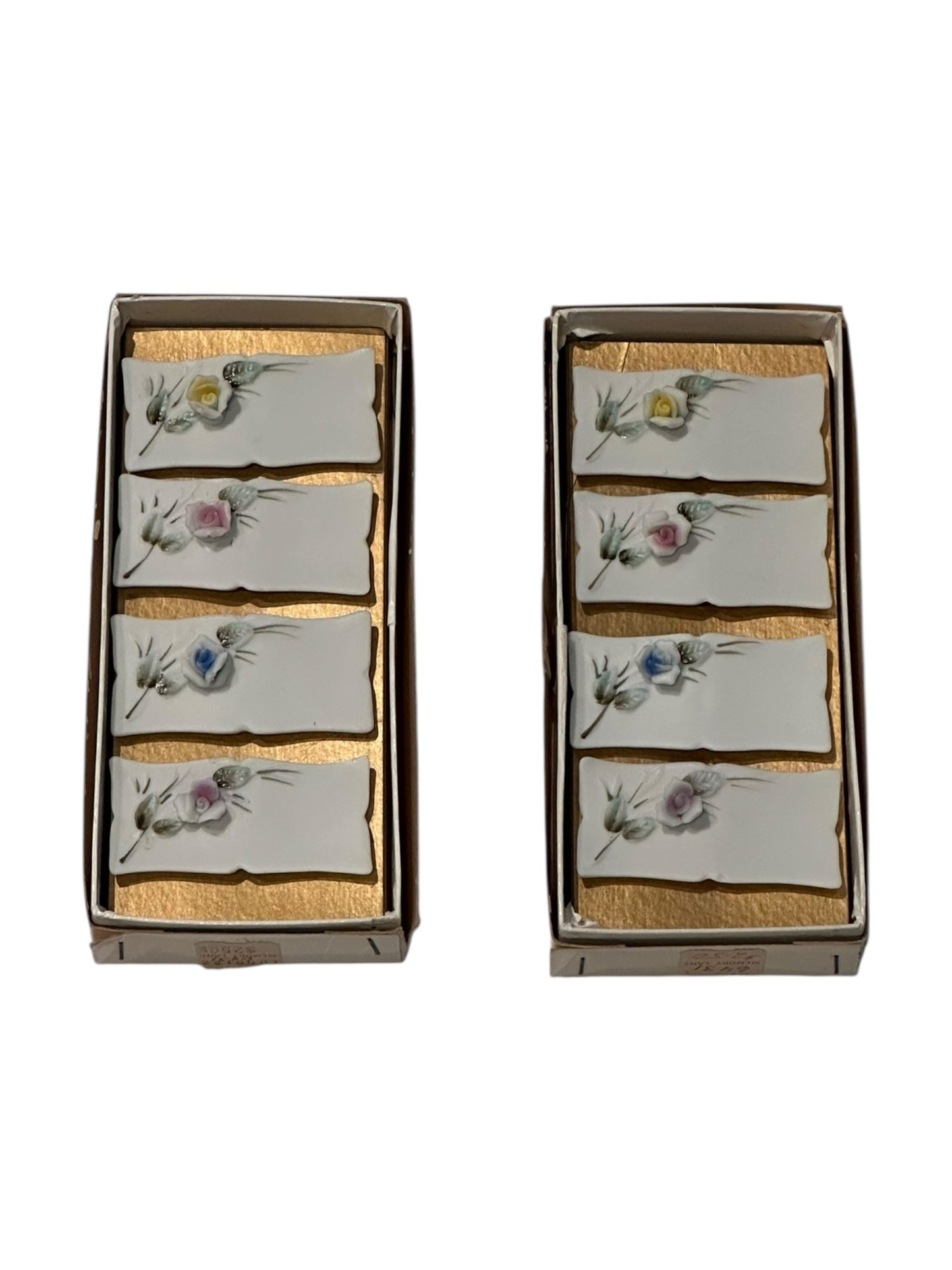 Set of eight porcelain place card holders with hand-painted pastel flowers, shown in two boxes