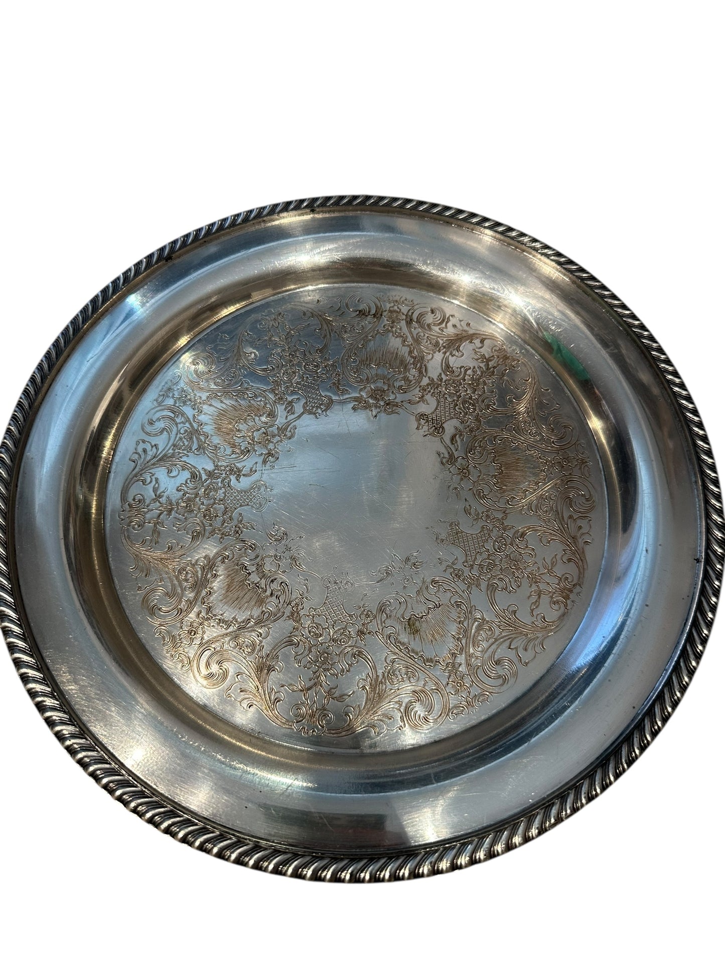 Vintage 11-inch silverplate serving tray, angled view of ornate engraved floral scrollwork interior