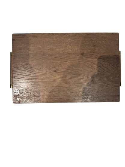 Underside of the small wooden tray showing grain, brass handle mounts and a label