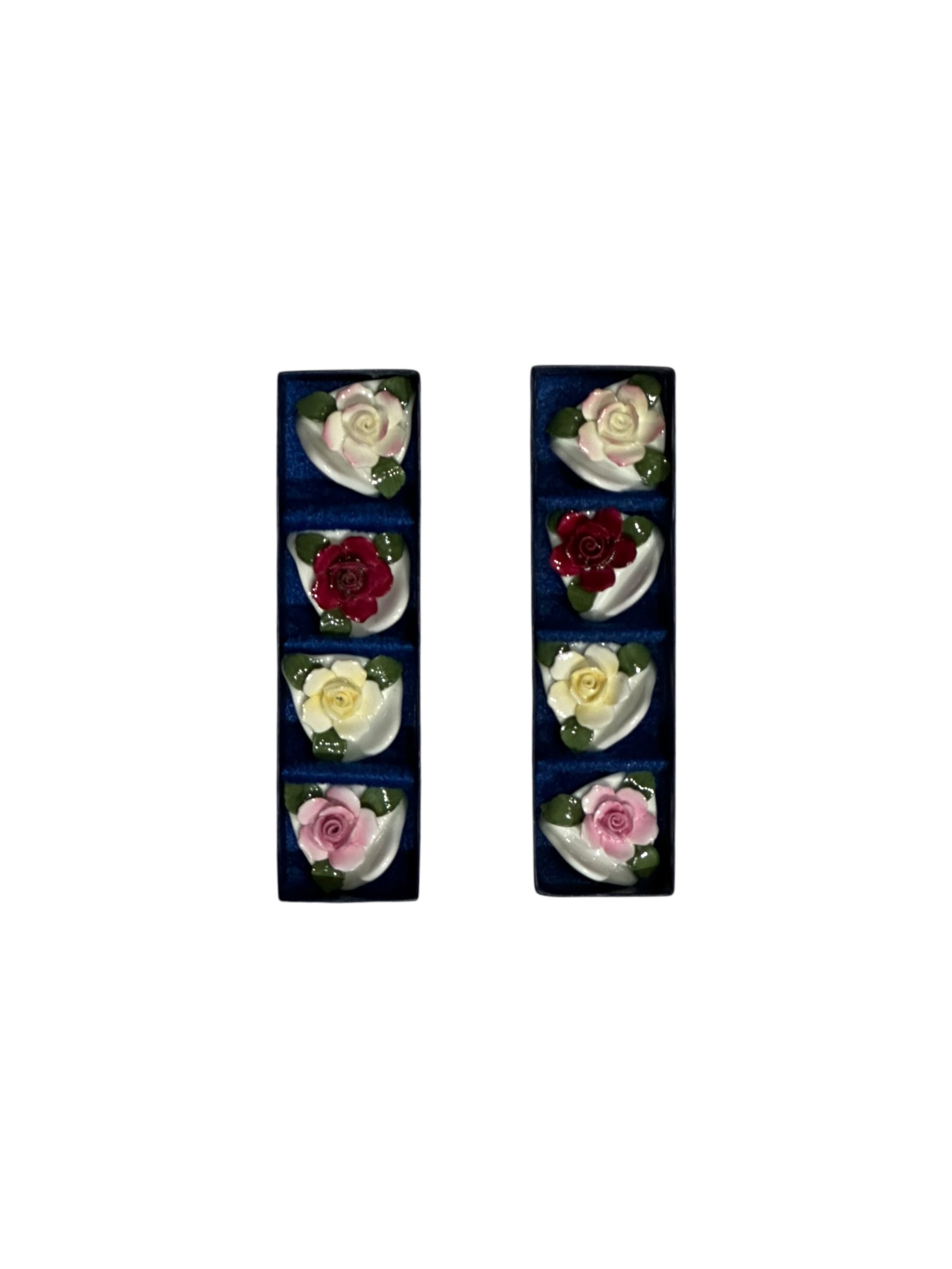 Porcelain rose place card holders displayed in two dark blue presentation boxes, top view