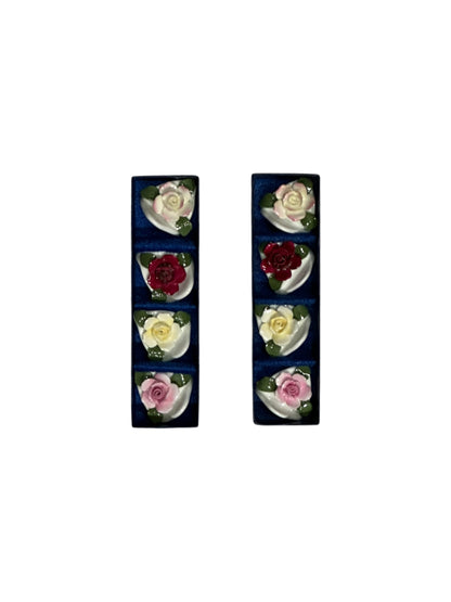 Porcelain rose place card holders displayed in two dark blue presentation boxes, top view