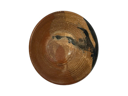 Studio pottery bowl interior in rust-brown glaze with throwing rings and a dark glaze splash