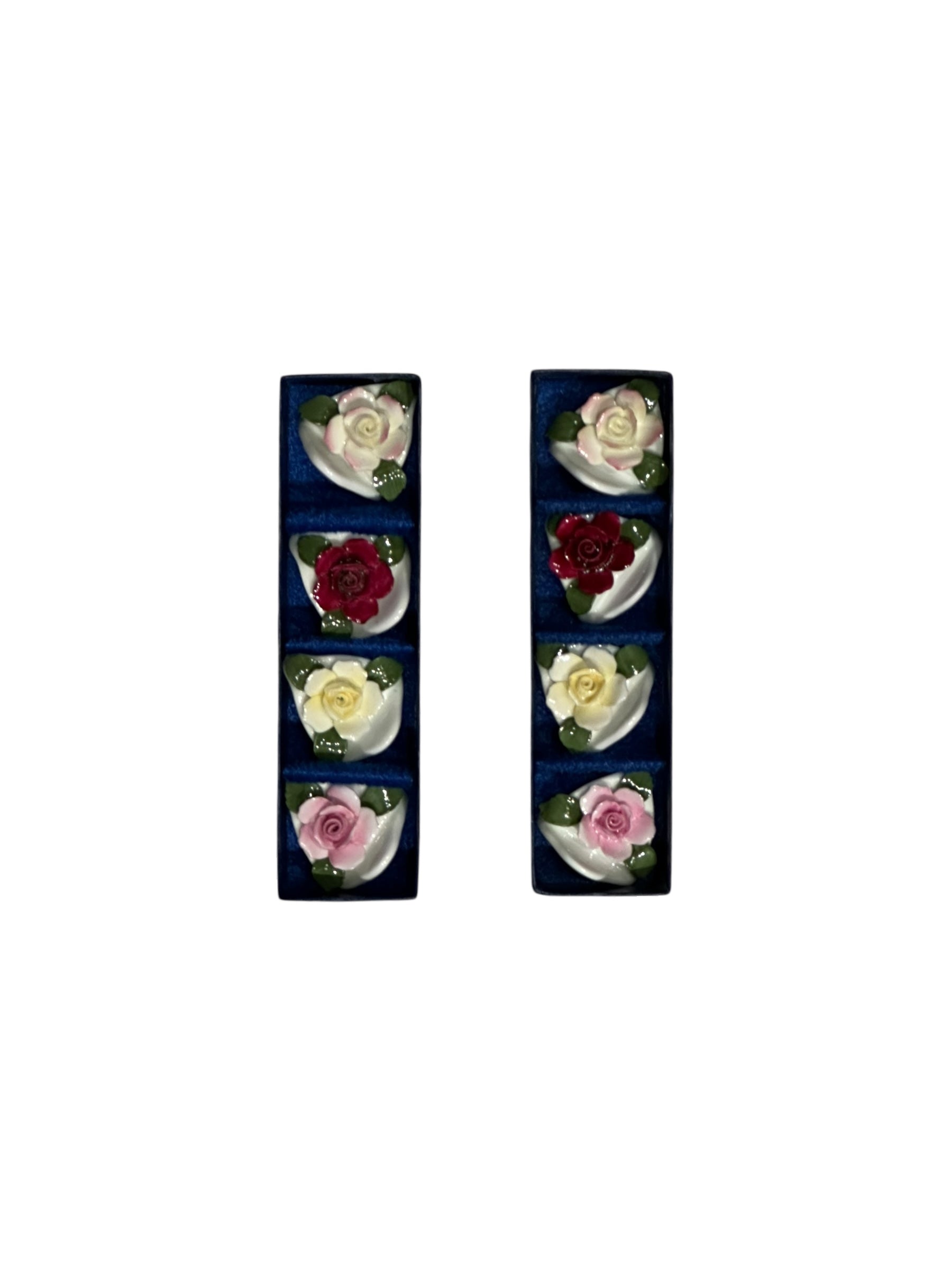 Set of eight porcelain rose place card holders in pink, red and cream, shown in two navy boxes