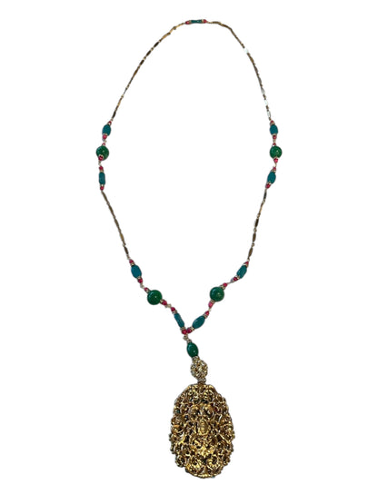 Pendant necklace displaying the ornate gold filigree reverse of the pendant on a beaded chain