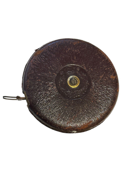Antique leather-cased retractable tape measure showing embossed center fitting, front