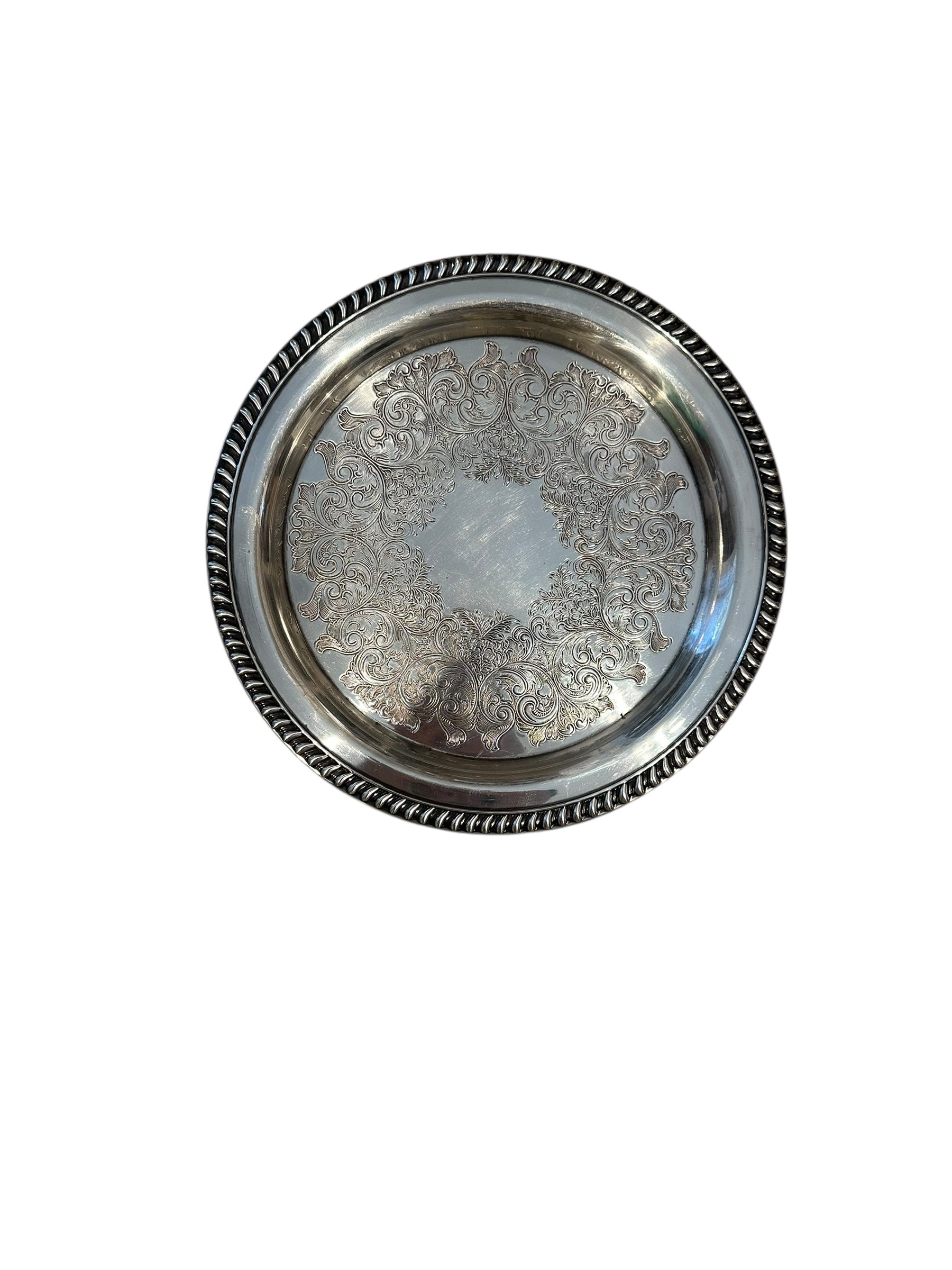 Vintage 11-inch silverplate serving tray, angled view of engraved scrollwork center and gadrooned rim