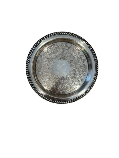 Vintage 11-inch silverplate serving tray, angled view of engraved scrollwork center and gadrooned rim