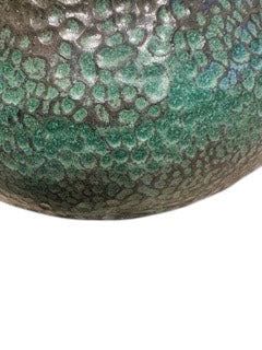 Close-up of green stoneware bowl's lower exterior showing mottled crawling green-bronze glaze.