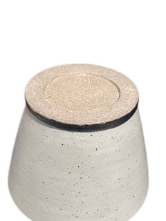 Close-up of white stoneware vessel's top, unglazed sandy rim above dark collar.