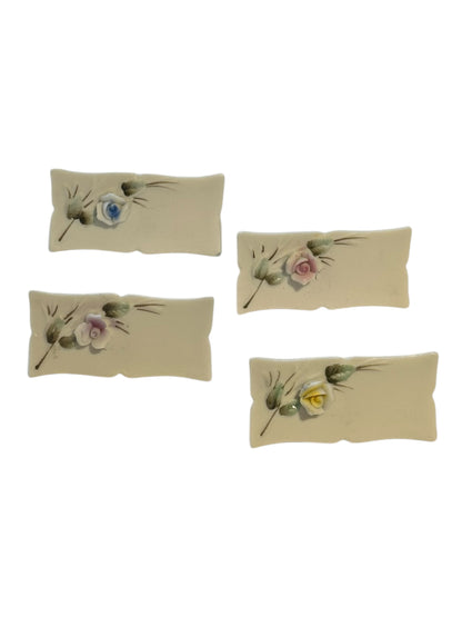 Four porcelain place card holders with hand-painted blue, pink and yellow flower sprays, top view