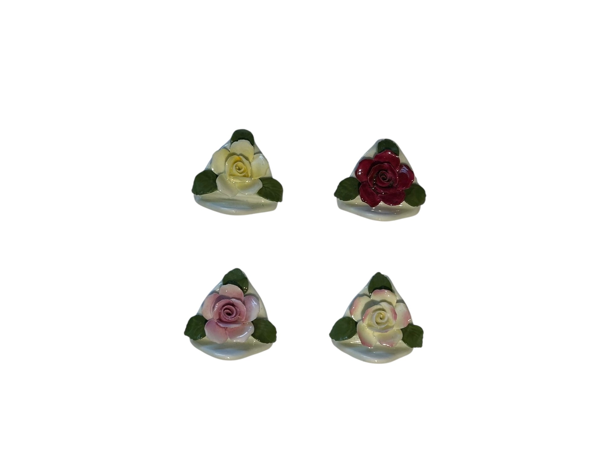 Four sculpted porcelain rose place card holders in cream, red and pink on curved white bases