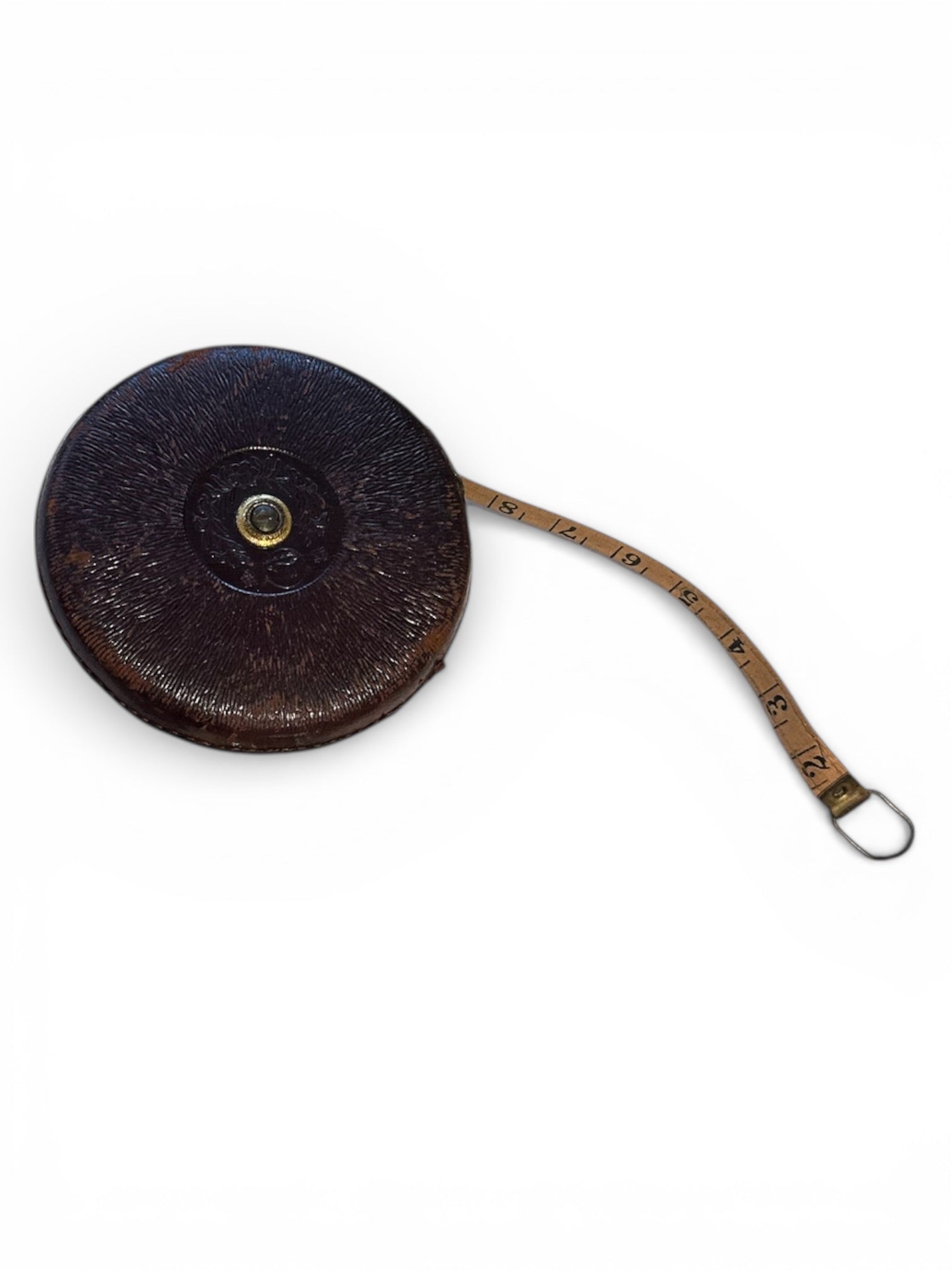 Antique retractable tape measure in tooled leather case with cloth tape partly extended