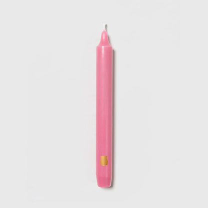 Rose pink Trudon Madeleine taper candle upright with an embossed gold crest