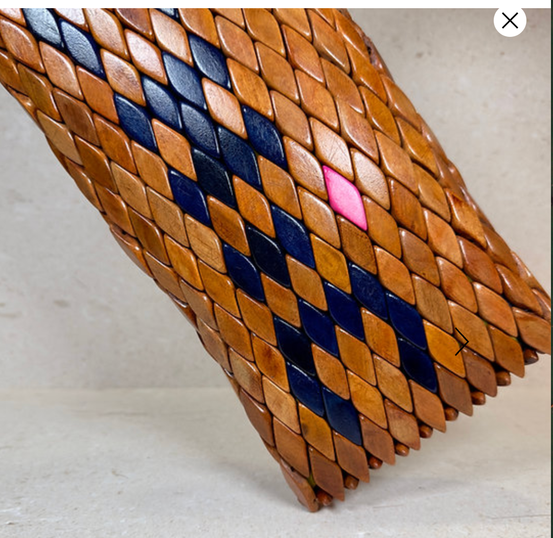 Ma'aM Kind woven wood clutch in saddle tan, close-up of scale-tiled surface with navy and pink accents