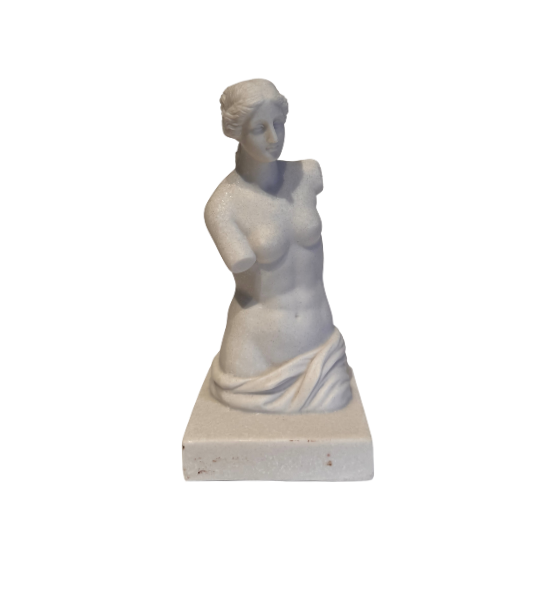 Off-white classical Venus de Milo sculpture depicting a female figure with wavy hair arranged in a bun, a softly detailed face, an armless torso, and draped fabric around the hips. The sculpture stands on a rectangular base with subtle speckling and minor surface discoloration.