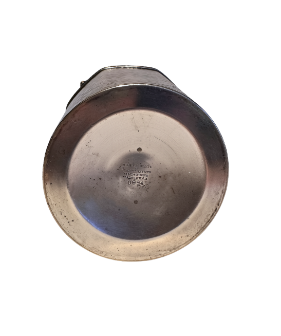 A vintage silver-tone metal ice bucket with a hexagonal, slightly tapered body and a textured hammered surface. A narrow decorative band with a repeating leaf pattern encircles the upper rim. A flat metal carrying handle is attached to opposite sides of the bucket and can be raised or lowered. The matching metal ice tongs feature textured arms ending in three-pronged bird claw shapes. The bucket's interior has a hammered texture with visible darkening and discoloration at the bottom.