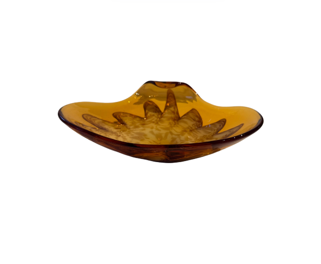 Vintage translucent amber glass dish with an irregular curved rim and a raised cream-and-brown swirled floral starburst design in the center.