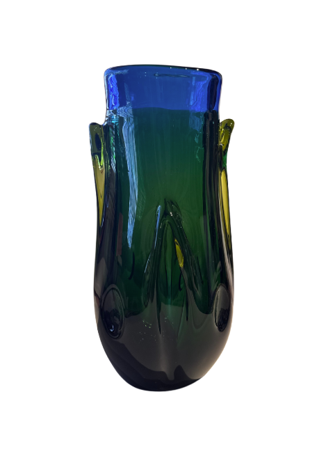 Tall, sculptural glass vase with a deep emerald green body, rounded base, and thick cobalt blue rim. Raised, flowing glass accents extend along the sides, incorporating translucent yellow-green details. The vase has an irregular oval opening and a glossy, reflective surface.