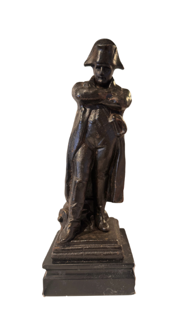 Front View of Dark cast iron statue depicting Napoleon Bonaparte standing with his arms crossed, wearing a bicorne military hat, long overcoat, and boots. The figure stands on a stepped rectangular black marble base.