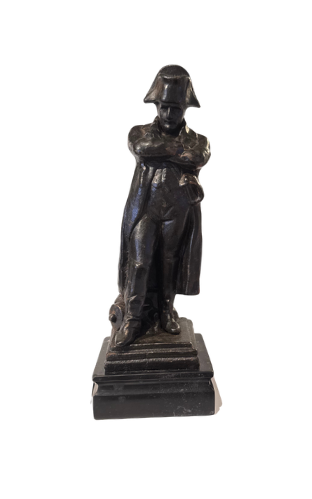Front View of Dark cast iron statue depicting Napoleon Bonaparte standing with his arms crossed, wearing a bicorne military hat, long overcoat, and boots. The figure stands on a stepped rectangular black marble base.