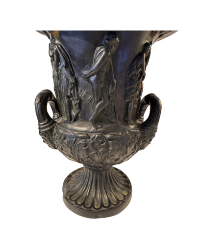 Close Up view, Black faux-bronze Neoclassical Medici urn with green patina accents, measuring 11 inches tall and 9 inches in diameter. The Campana-shaped vessel features a wide flared rim with egg-and-dart detailing, raised Greco-Roman figures in various poses, grapevine and leaf borders, and two reeded loop handles with bearded mask decorations. An intricate floral and acanthus leaf design surrounds the lower bowl, which rests on a fluted circular pedestal base.