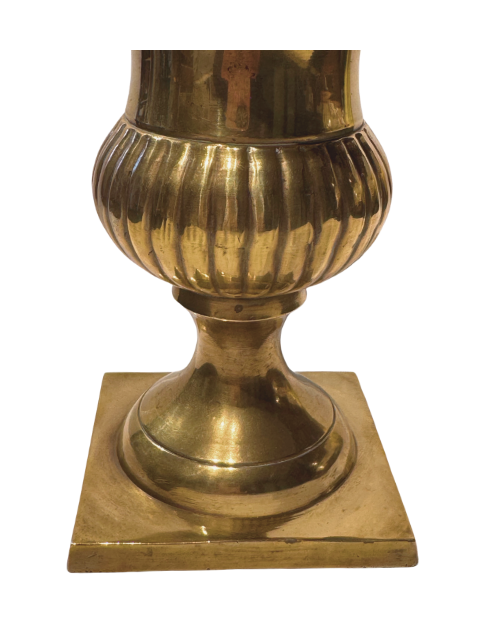 Close-up of the lower section of a brass decorative urn featuring a rounded, vertically fluted body, tapered pedestal stem, and square base. The polished gold-tone surface displays light scratches, tarnishing, and minor wear.