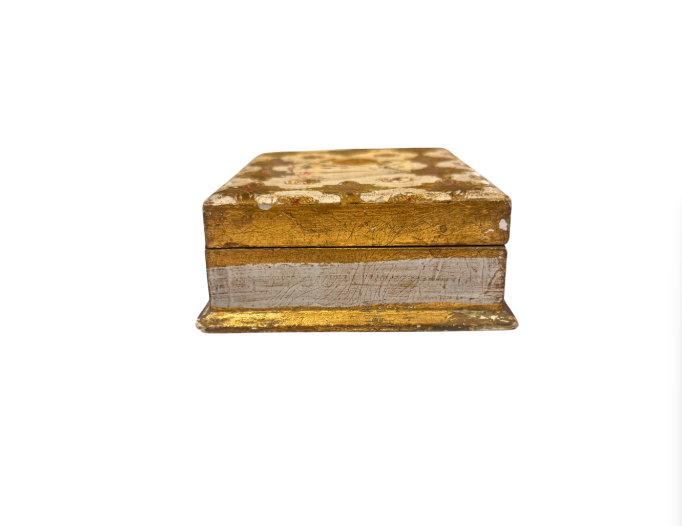 Side Profile: Side view of a vintage Florentine wooden box highlighting its worn gold finish, ivory-painted sides, and decorative stepped base.