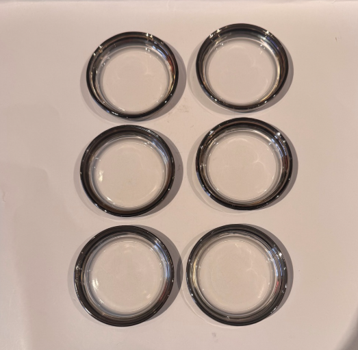 Overhead view of six round Mid-Century Modern glass coasters featuring transparent centers and metallic silver fade borders.