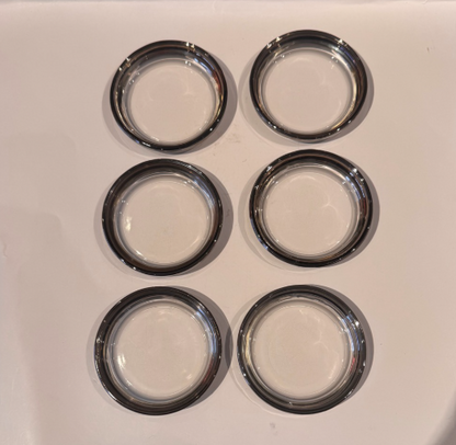Overhead view of six round Mid-Century Modern glass coasters featuring transparent centers and metallic silver fade borders.