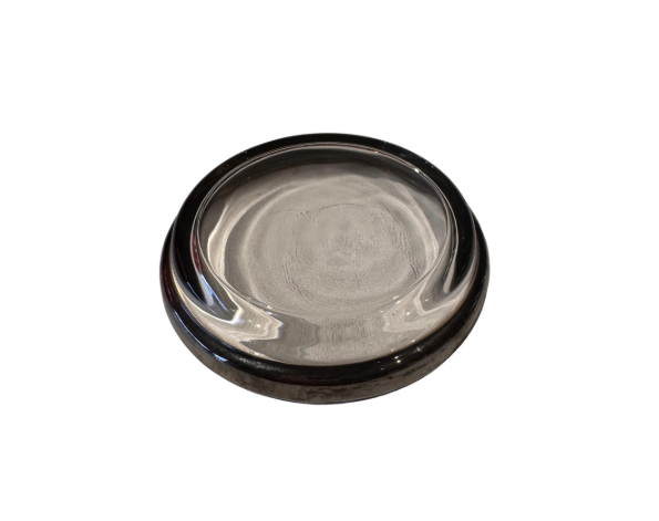 Angled underside view of a vintage silver fade glass coaster showing the glass base and signs of surface wear.