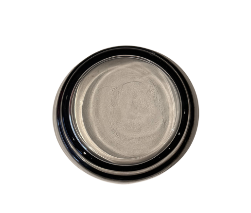 Bottom view of a vintage round glass coaster with a circular platinum-tone fade finish and visible surface wear.