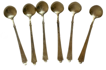 Close-up of the gold-washed sterling backs of the six demitasse spoons showing hallmarks stamped on each handle.