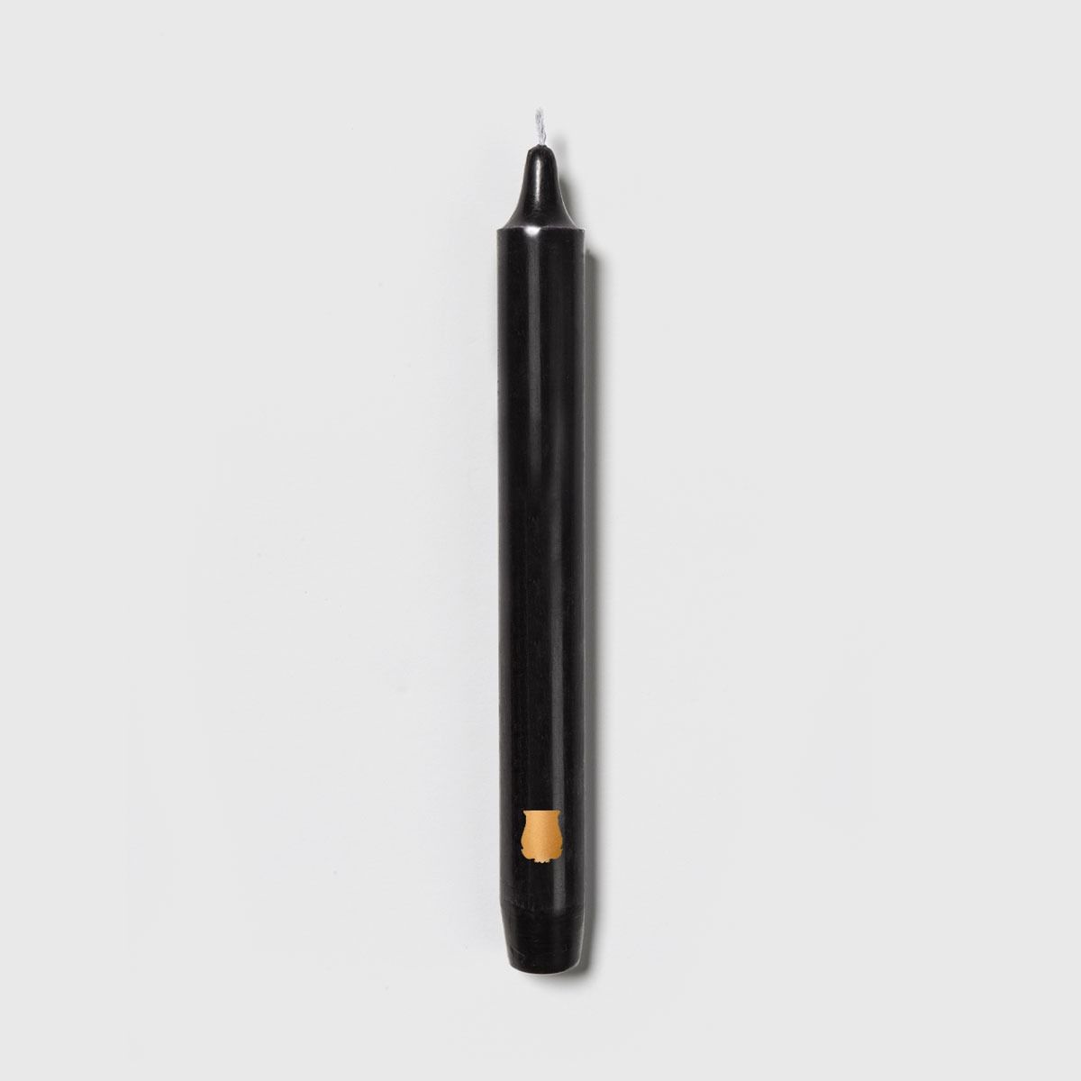 Single Trudon Madeleine black taper candle with gold Trudon crest seal near the base